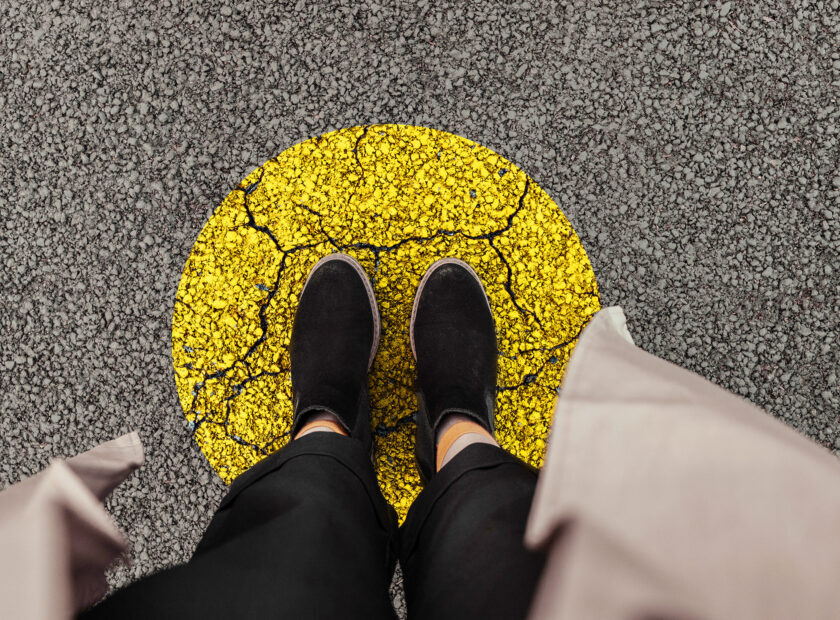 Woman legs in black shoes stands on a yellow circle of the road, top view. Leave your comfort zone for personal development